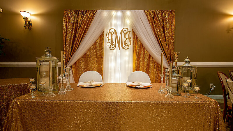 Table with gold table cloth and gold curtain backdrop with candle decorations